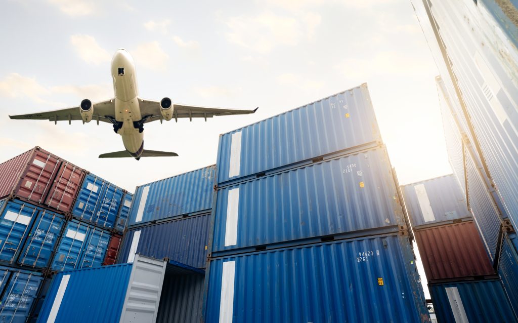 letecká logistika nákladní letadlo letící nad hromadou logistických kontejnerů nákladní a přepravní činnosti 1 1